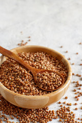 Raw dry buckwheat grain  in a bowl with a spoon
