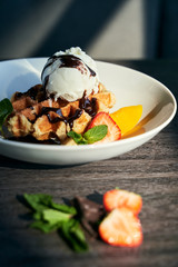 Belgian waffle with ice cream, strawberries, orange and chocolate