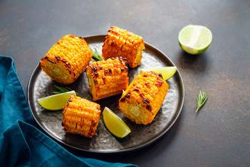 Roasted or grill corn cob with olive oil and salt on a black plate.