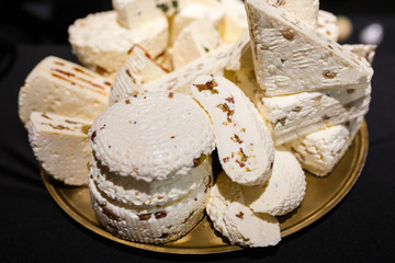 Cheese platter with organic cottage cheeses with fruits and nuts and vegetable toppings on wooden table.