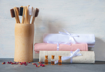Eco-friendly personal hygiene items made of natural materials. Toothbrushes, linen towels, and bottles of rose oil.