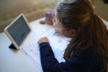 Fototapeta na wymiar Real 10 year old girl is doing homeschooling, learning at home, doing homework 