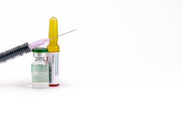 An injection needle placed on a vial with one ampoule having Corona virus Vaccine label.