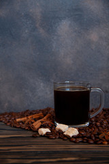 Cup with americano and coffee beans on a wooden table. Copy space for your text.