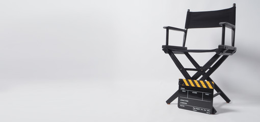 Clapper board or movie slate with director chair. It's black with yellow color on white background.