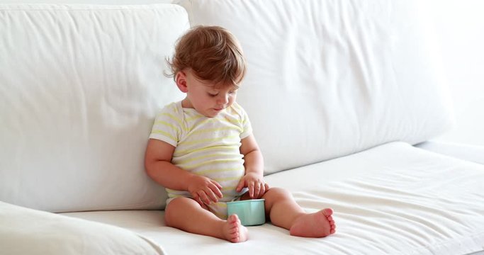 One year old baby toddler boy sitting on sofa coughing, sweet adorable infant child