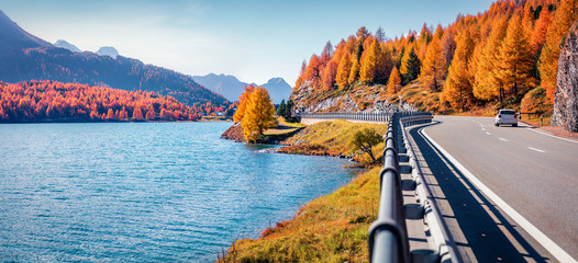 Asphalt road on the shore of Sils lake. Panoramic morning view of Swiss Alps. Colorful autumn scene of Switzerland, Europe. Traveling concept background..