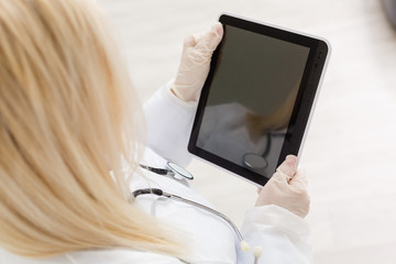 Female runette doctor using tablet, intelligent and lovely woman with the gadget and stethoscope in the white background