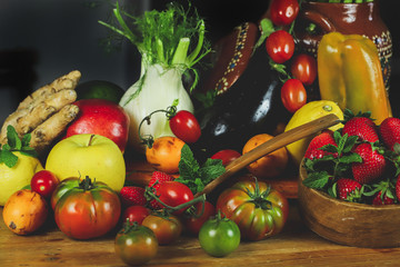 
closeup of fruit and vegetables arranged on a wooden table in a rustic composition and wrapped in a warm light