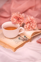 Pausa relax con libro, tè caldo e peonie rosa