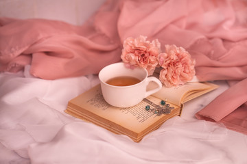 Pausa relax con libro, tè caldo e peonie rosa © Martina