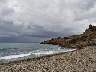 Fototapeta na wymiar Rocky beach with storm clouds at Cabo de Gata, Almeria, Spain