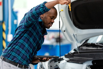 Car mechanic checking the oil level in the car