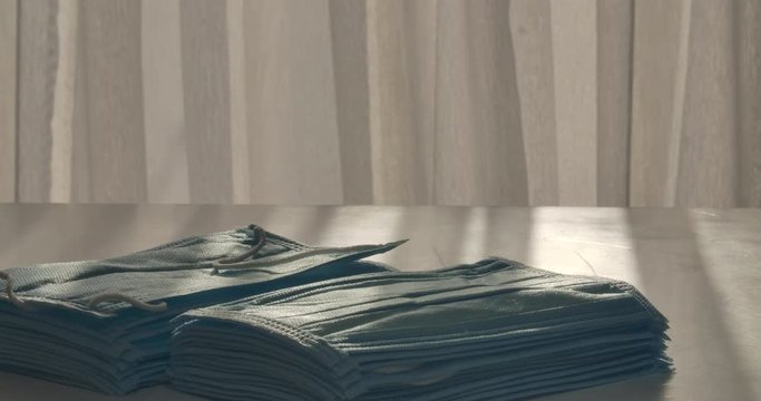 Hands of female doctor or volunteer putting stacks of medical face masks on the table. Close-up of protective masks against coronavirus disease spreading. Covid-19, pandemic. Cinema 4k ProRes HQ.