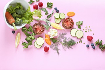 Creative layout made of kitchen bowl with fresh vegetables, berries and herbs on pink background. Flat lay