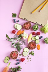 Creative layout made of kitchen bowl with fresh vegetables, berries and herbs on pink background. Flat lay
