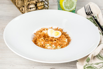 Salad with an egg in a white deep plate, shot in the decor