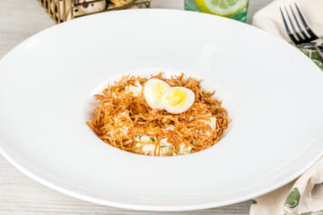 Salad with an egg in a white deep plate, shot in the decor