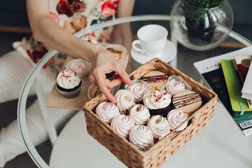 Beautiful caucasian female with short dark hair in a white cozy sweater holds a yoummy marshmallow and smiles
