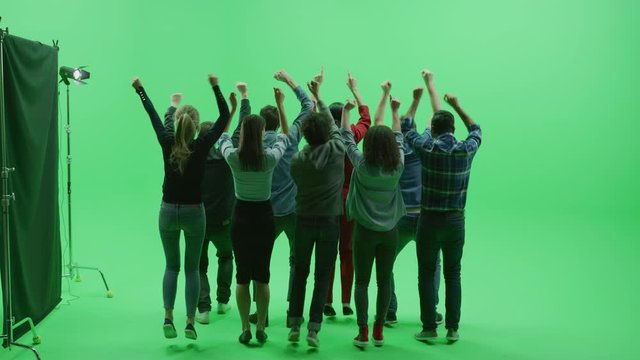 Green Screen Chroma Key Studio: Two Rows of Nine Diverse Fans Cheering, Jumping, Applauding with Hands in the Air at the Public Sport Event, Concert, Festival, Party. Back View Full Shot. Slow Motion