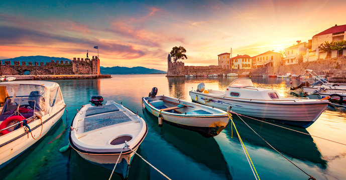 Great evening view of Gulf of Corinth, Greece, Europe. Attractive sunset on popular touristic destination - Nafpaktos port. Calm seascape of Ionian sea. Traveling concept background.
