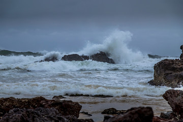 Rocks next to the beach of the Camel Rock bay in New South Wales, Australia at a cloudy and windy day in summer with strong waves in the ocean. 