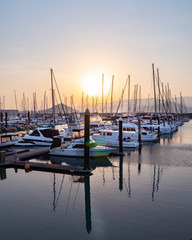Sunset Marina. Boats & yachts docked at sea. Airlie beach boat harbour waterfront sunset view. Reflections in water. Mountain landscape background. Whitsundays Islands, Queenstown, Australia