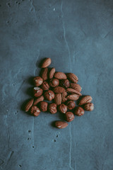 A close-up of a heap of peeled almond and hazel nuts on a concrete blue texture. A culinary concept. Copy space