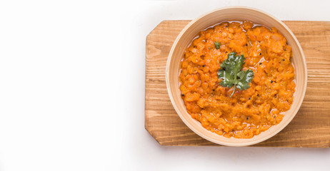 Dhal Indian lentil soup with cilantro in a bowl on a wooden plank. White background. Copy space
