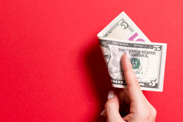 Top view of female hand holding a pack of money on colorful background. Five dollars. Business...