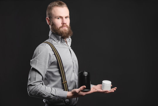 Handsome young man presents car parts on a gray background. The concept of sales and testing of goods