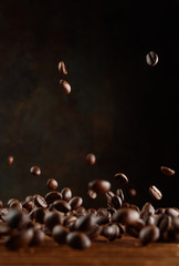 Obraz premium Many roasted coffee beans flying in the air over a wooden table. Selective focus