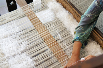 A woman is using traditional weaving machines to weave songket. Songket is a Malay traditional...
