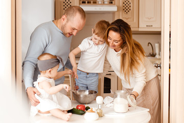 Obraz na płótnie Canvas Family cooks together in the kitchen and looks happy, mom, dad, baby, brother, sister, morning, love, care, laughter, fun, home