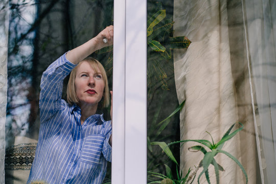 A female hand opens a window with water drops. Closes the window. In the rainy weather. Closeup. - Powered by Adobe