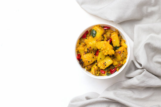 Aloo gobi traditional Indian dish of cauliflower and potato vegetables and spices in a bowl on a white background. Copy space