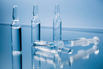 Syringe and glass ampoules on a blue background. Injection preparation 