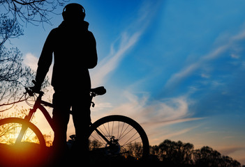 Silhouette of a cyclist at sunset against the sky