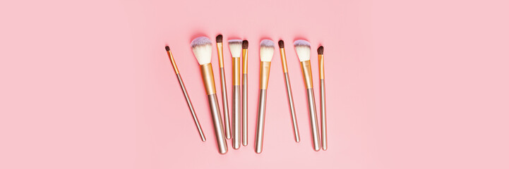 Cosmetic Makeup brushes on pink background. Flat lay, top view, overhead. Makeup accessories, mockup, template. Horizontal long banner for web design
