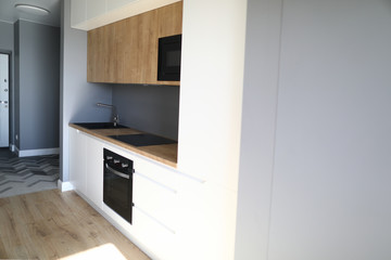 Close-up of kitchen furniture in new luxury apartment. Room with modern interior design. Black sink microwave and cookstove. Renovation in posh flat concept