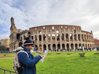 Young man with blue coat looking for information about Coliseum in a map in Rome,Italy
