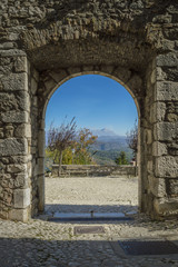 Breath-taking view of the mountains framed by the historic gate of the ancient village of Collalto Sabino near Rieti, Lazio, Italy