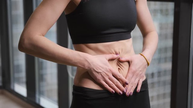 Athletic girl of Caucasian in sportswear,black leggings and top,girl strokes abc cubes on her stomach with her hands,sports and fitness at home,concept of training and Wellness