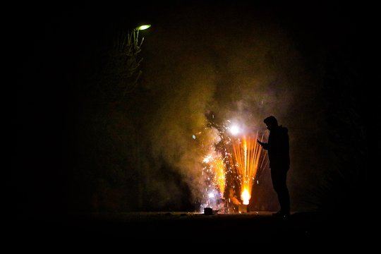 Silhouette Man Standing By Illuminated Fireworks At Night
