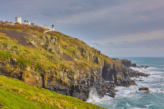 Image of the Lizard Point Lighthouse, with the headland, cliffs, sea and overcast sky. Lizard Point, cornwall, UK