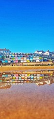 Obraz premium Stock photo of a colourful view of the sea shore of the Essex small town Walton-on-the-Naze reflected in the sea water, with copy space.