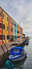 Fototapeta na wymiar Stock photo of with Burano (Venice) coloured houses and boats parked in front of them with copy space available.