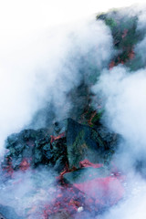 Steam rises from Icelandic hot springs with sulphur turning rock a green and red colour.