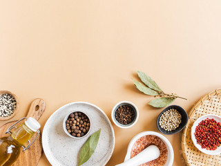Flat lay of small bowls various dry spices, wood kitchen utensils, olive oil in glass bottle on beige background. Top view. copy space