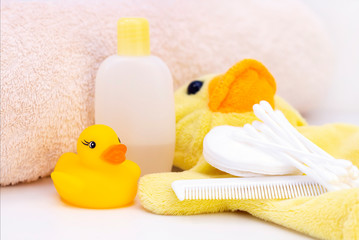 baby hygiene and bath items, shampoo bottle, baby soap, towel, yellow duck rubber toy, cotton pads and ear sticks, comb.